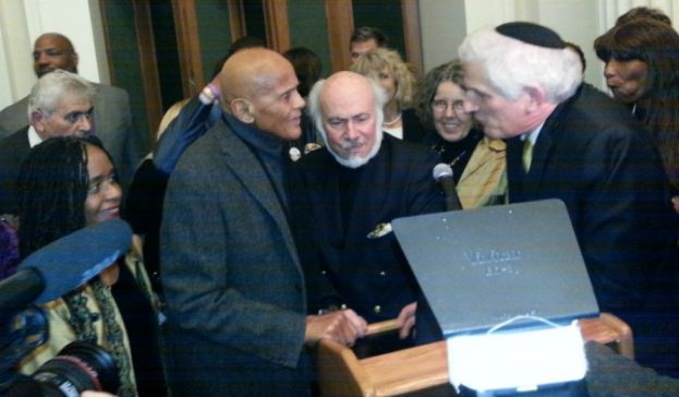 Actor Harry Belafonte (left) and social relevant photographer, Stephen Somerstein (center), overwhelmed by reception guests after giving opening remarks to mark the opening of Somerstein's exhibit, 